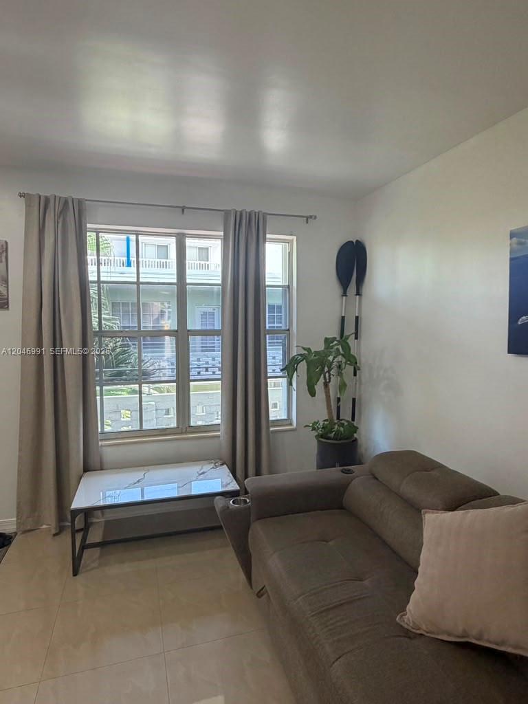 A living room features a brown sofa, a marble-topped coffee table, and a large window — 8550 Byron Ave # 2H, Miami Beach FL 33141, MIAMI BEACH, FL