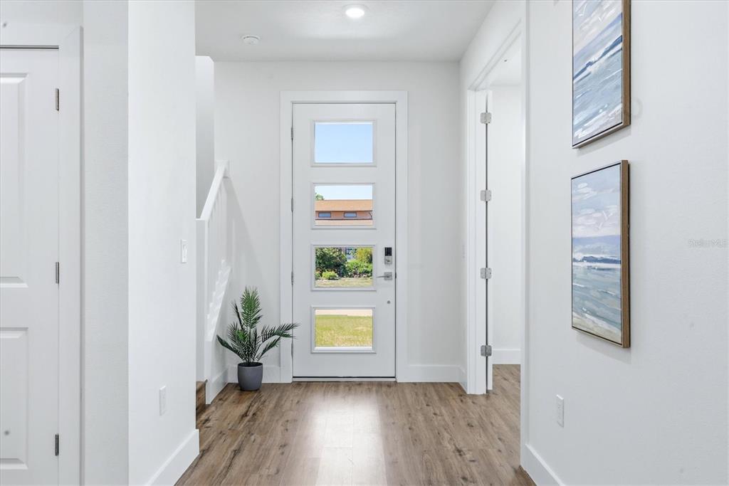 A bright entryway features a white front door with glass panels and wood-look flooring — 12387 MINOT AVENUE, PORT CHARLOTTE, FL