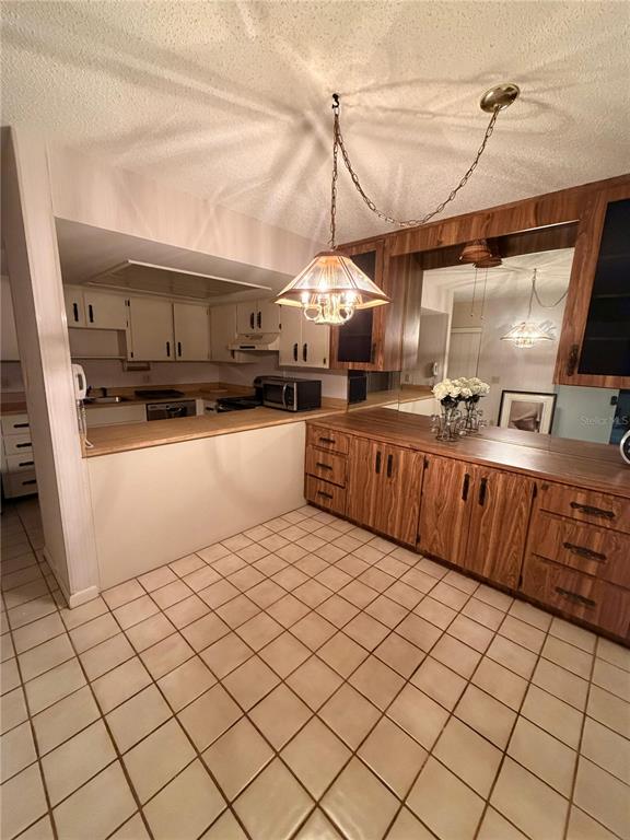 A kitchen and dining area feature wood cabinets, a tile floor, and a hanging light — 4150 S ATLANTIC AVENUE UNIT 126C, NEW SMYRNA BEACH, FL