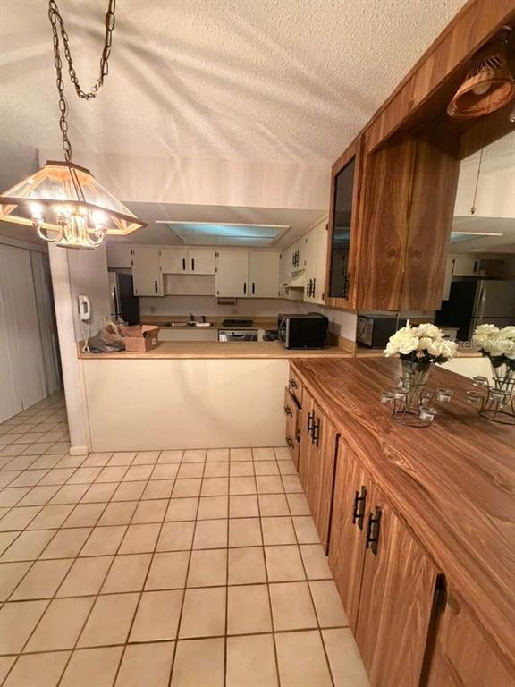 A kitchen features wood-look cabinetry, a breakfast bar, tiled flooring, and a hanging light fixture — 4150 S ATLANTIC AVENUE UNIT 126C, NEW SMYRNA BEACH, FL