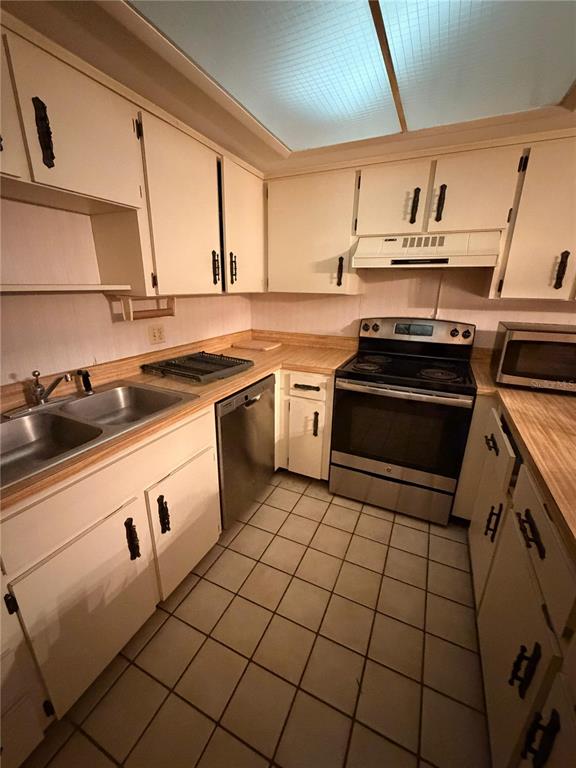 A kitchen features white cabinets, laminate countertops, a stainless steel stove, and tiled flooring — 4150 S ATLANTIC AVENUE UNIT 126C, NEW SMYRNA BEACH, FL