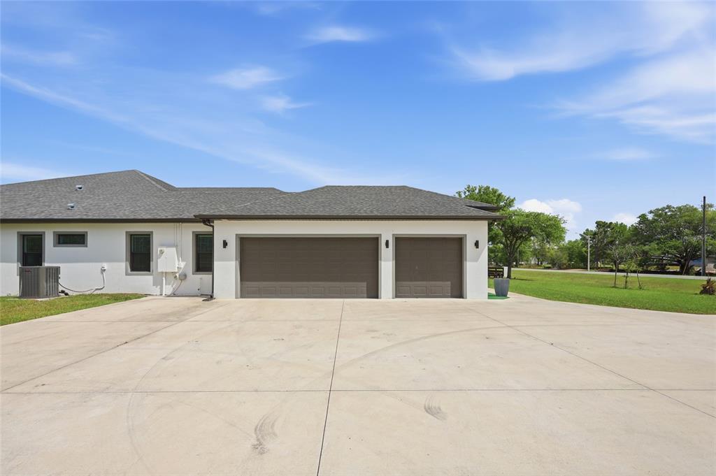 A wide concrete driveway leads to a three-car garage attached to a white house — 5700 BANCROFT BOULEVARD, ORLANDO, FL