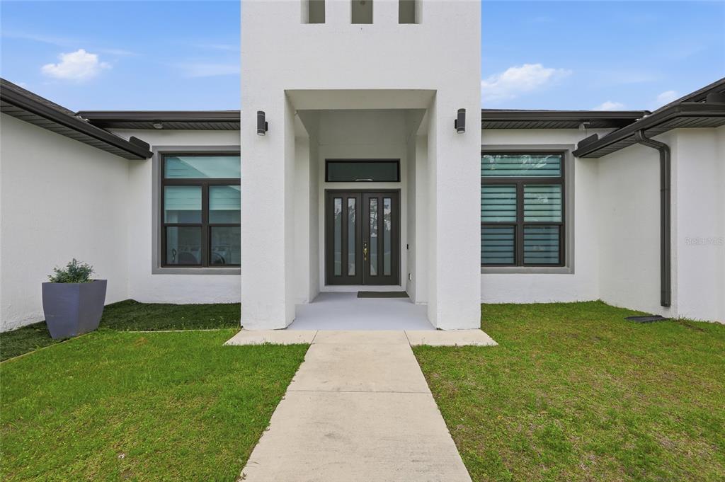 The exterior of a modern white house features a central entryway with double doors — 5700 BANCROFT BOULEVARD, ORLANDO, FL