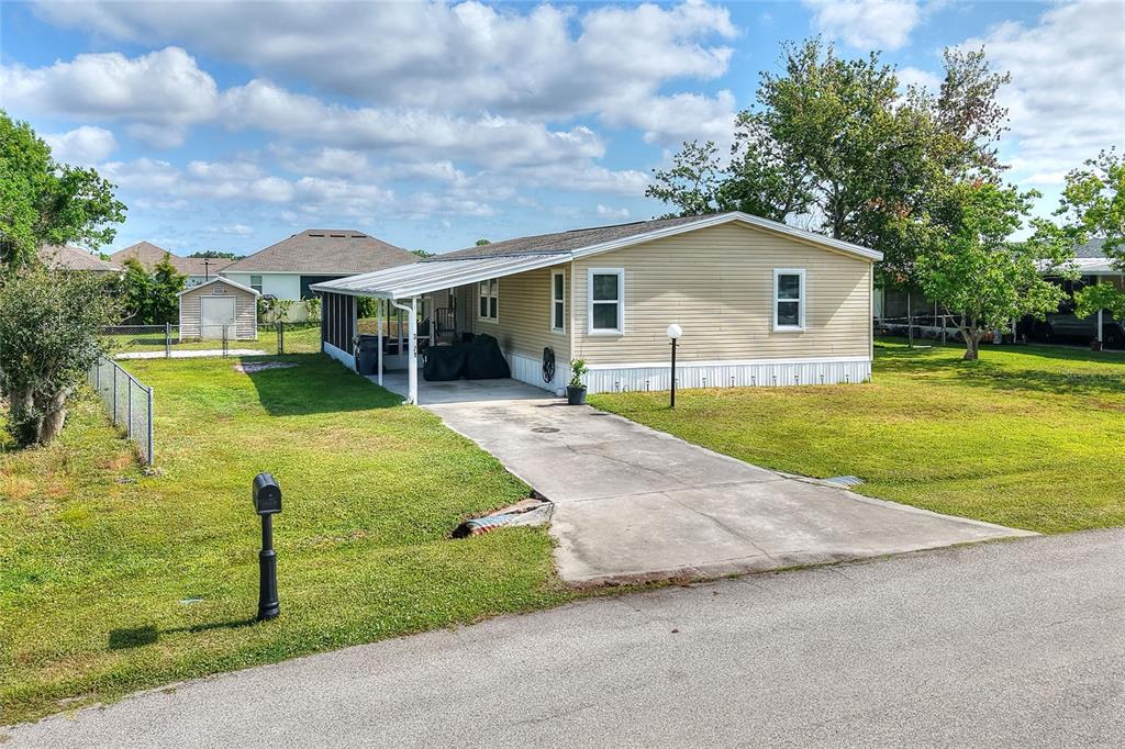 A single-story manufactured home with light siding, a carport, and a concrete driveway — 3071 KEUKA LOOP, LAKELAND, FL