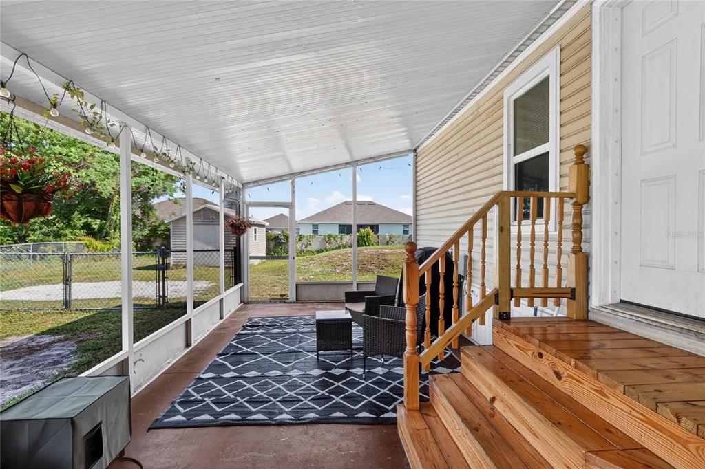 A screened-in porch features a concrete floor, wooden stairs, and a view of a backyard — 3071 KEUKA LOOP, LAKELAND, FL
