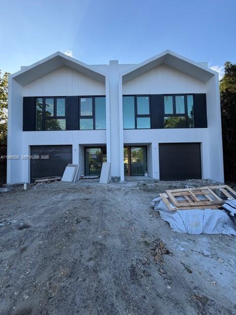 A modern duplex features white vertical siding, dark window frames, and two attached garages — 2800 SW 38th Ct, Miami FL 33134, MIAMI, FL