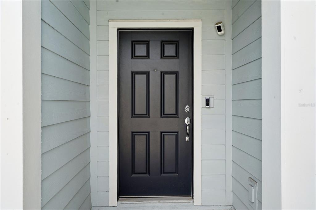 A black front door with six panels is set within light blue horizontal siding — 1995 CANNY COVE, WINTER PARK, FL