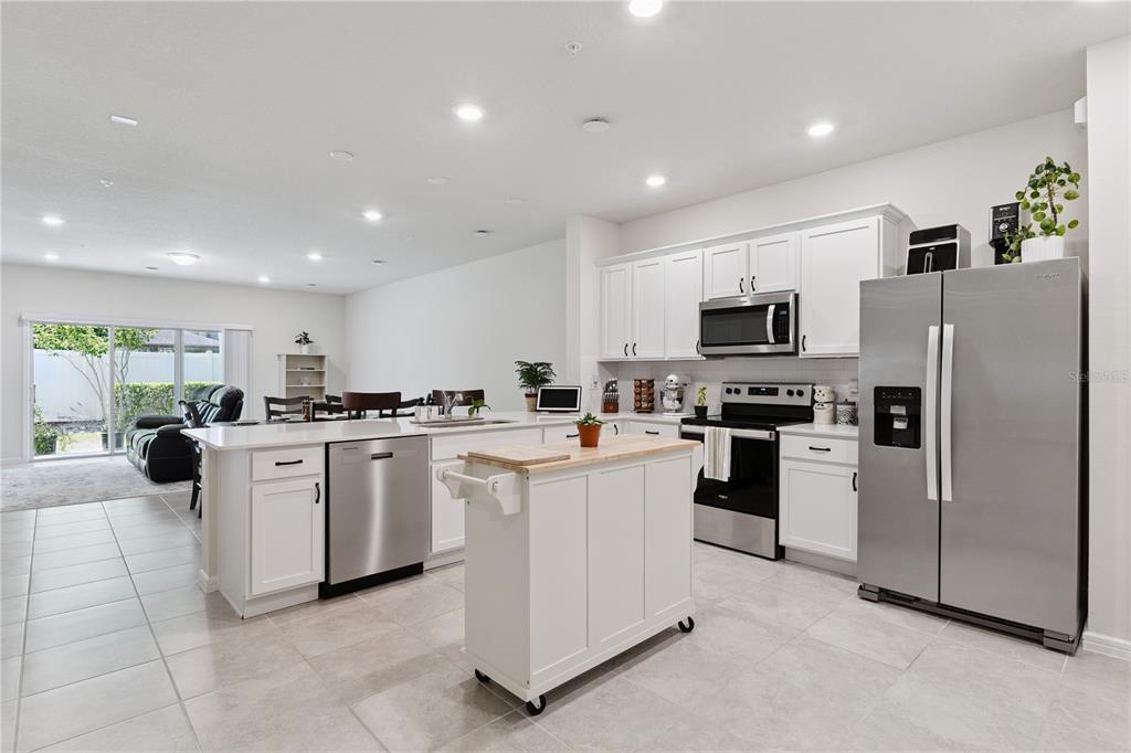 A kitchen with white cabinets, stainless steel appliances, and a portable island on tile floors — 1995 CANNY COVE, WINTER PARK, FL