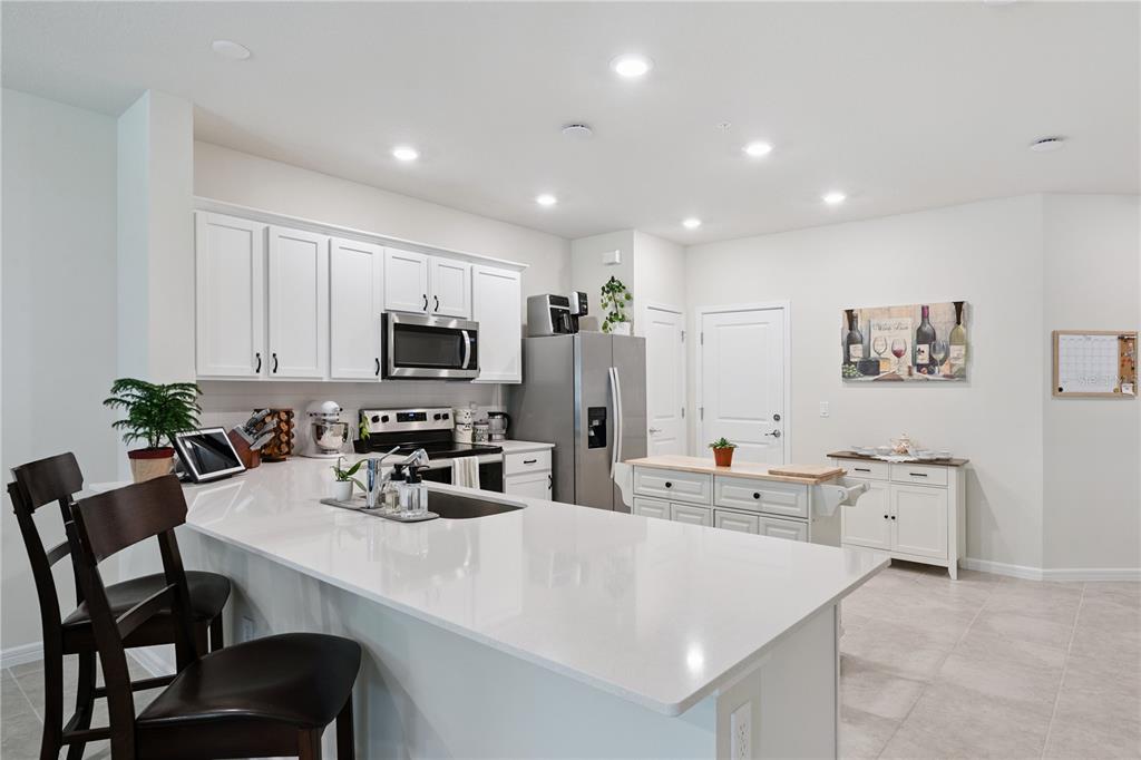 A kitchen features white cabinets, stainless steel appliances, a quartz island, and tile flooring — 1995 CANNY COVE, WINTER PARK, FL