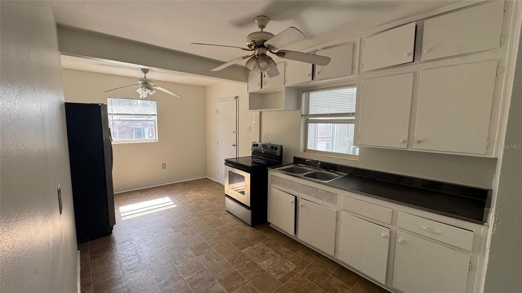 A kitchen with white cabinets, a stainless steel stove, and a ceiling fan — 13920 3RD STREET, DADE CITY, FL