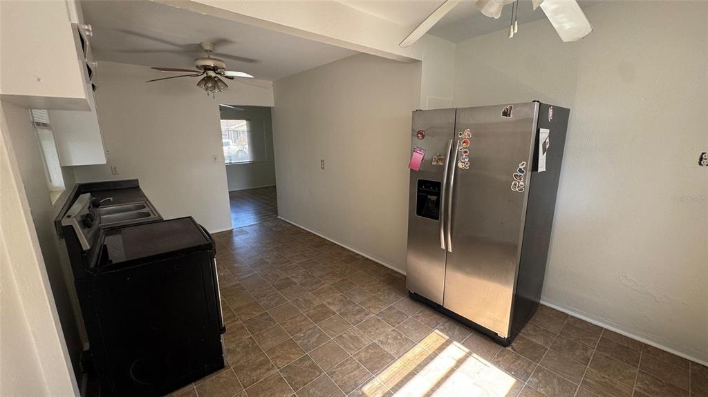 A kitchen features a stainless steel refrigerator, black stove, and tiled flooring — 13920 3RD STREET, DADE CITY, FL