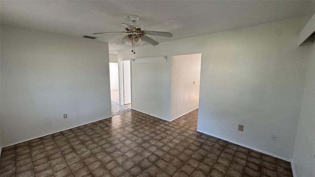 An interior room features a ceiling fan, white walls, and brown square floor tiles — 13920 3RD STREET, DADE CITY, FL