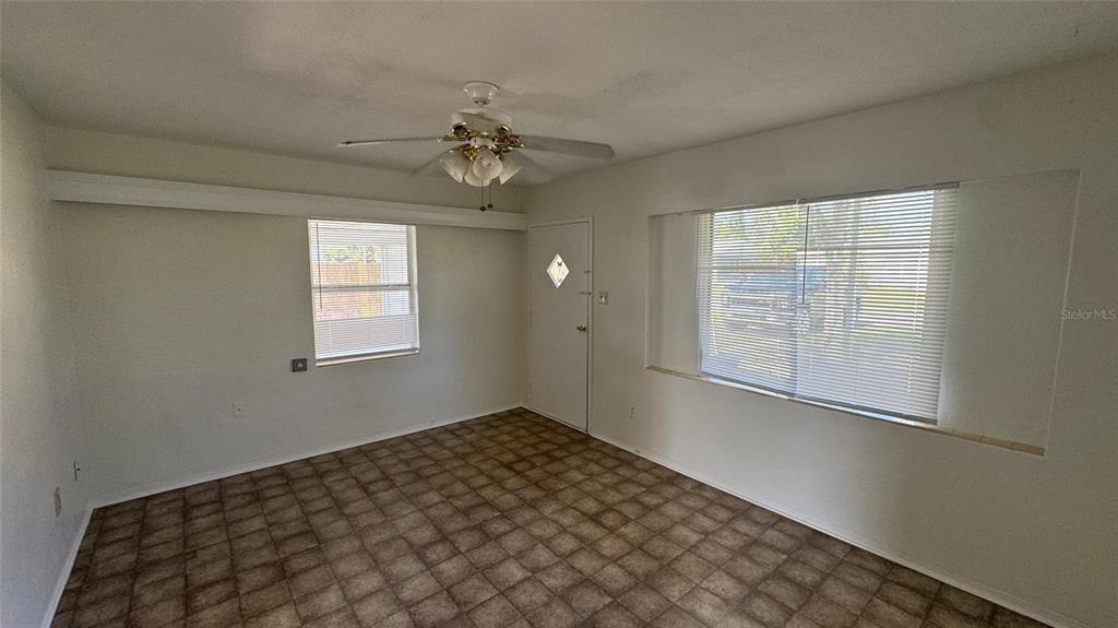 An empty room features a ceiling fan, tiled flooring, a white door, and two windows — 13920 3RD STREET, DADE CITY, FL
