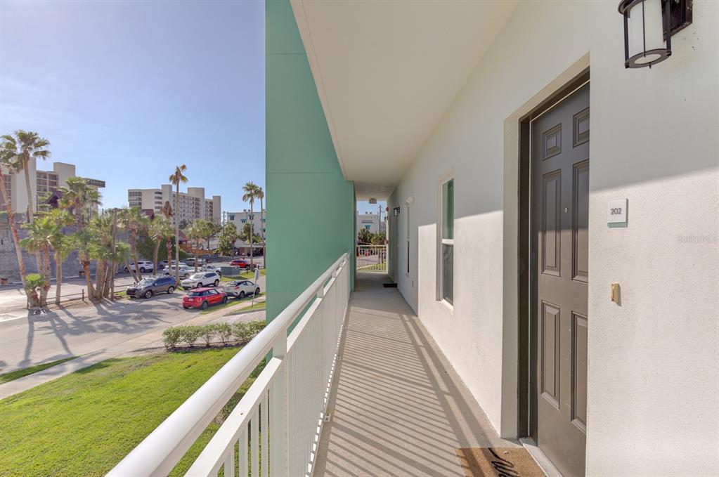 An exterior walkway with a white railing leads to a dark door labeled 202 — 15305 1ST STREET E UNIT 202, MADEIRA BEACH, FL