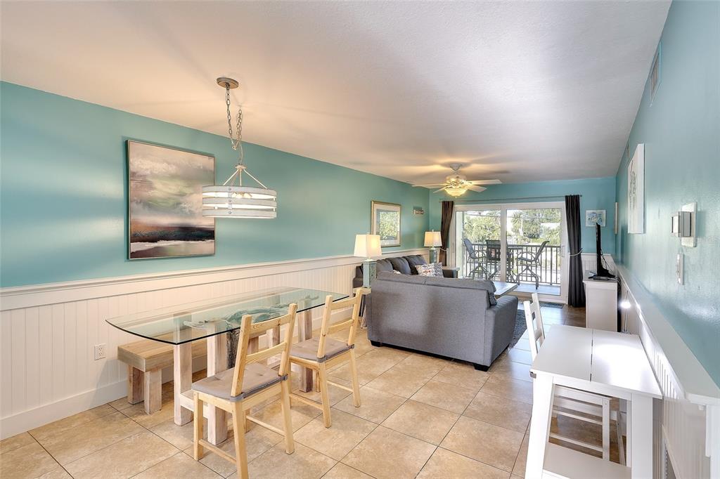 A dining area and living room with light blue walls, tile floors, and a balcony view — 4307 GULF DRIVE UNIT 207, HOLMES BEACH, FL