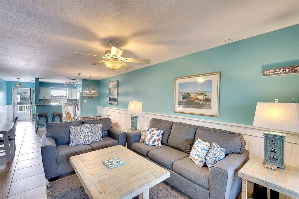 A living room with gray sofas, a light wood coffee table, and turquoise walls — 4307 GULF DRIVE UNIT 207, HOLMES BEACH, FL