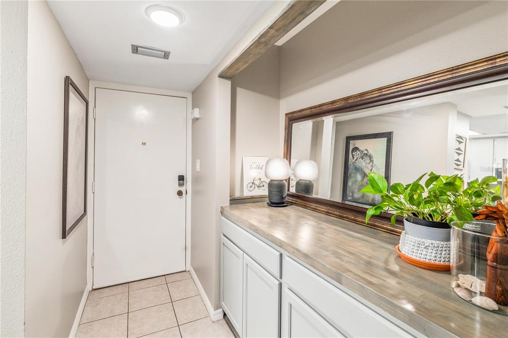 An entryway features a white door, tiled floor, light gray cabinets, and a large wall mirror — 90 S HIGHLAND AVENUE UNIT 402, TARPON SPRINGS, FL