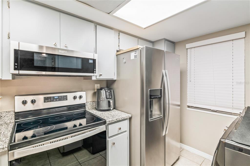 A kitchen features stainless steel appliances, light gray cabinets, and granite countertops — 90 S HIGHLAND AVENUE UNIT 402, TARPON SPRINGS, FL