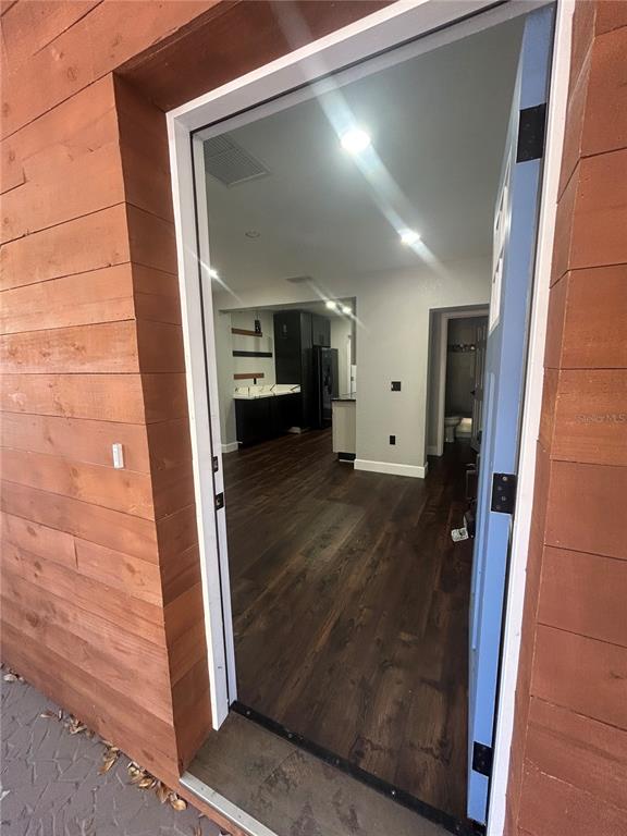 A view through an open doorway reveals a kitchen with dark cabinets and wood flooring — 1111 SE 6TH AVENUE, GAINESVILLE, FL