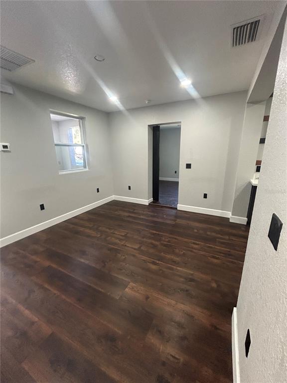 A room with light gray walls, dark wood-look flooring, and a doorway leading to another room — 1111 SE 6TH AVENUE, GAINESVILLE, FL