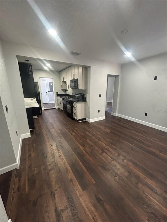 An open-concept kitchen with dark wood flooring and light cabinetry connects to a living area — 1111 SE 6TH AVENUE, GAINESVILLE, FL