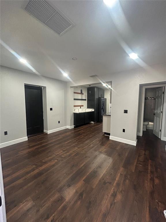 A room with dark wood flooring, light gray walls, and a small kitchen area — 1111 SE 6TH AVENUE, GAINESVILLE, FL