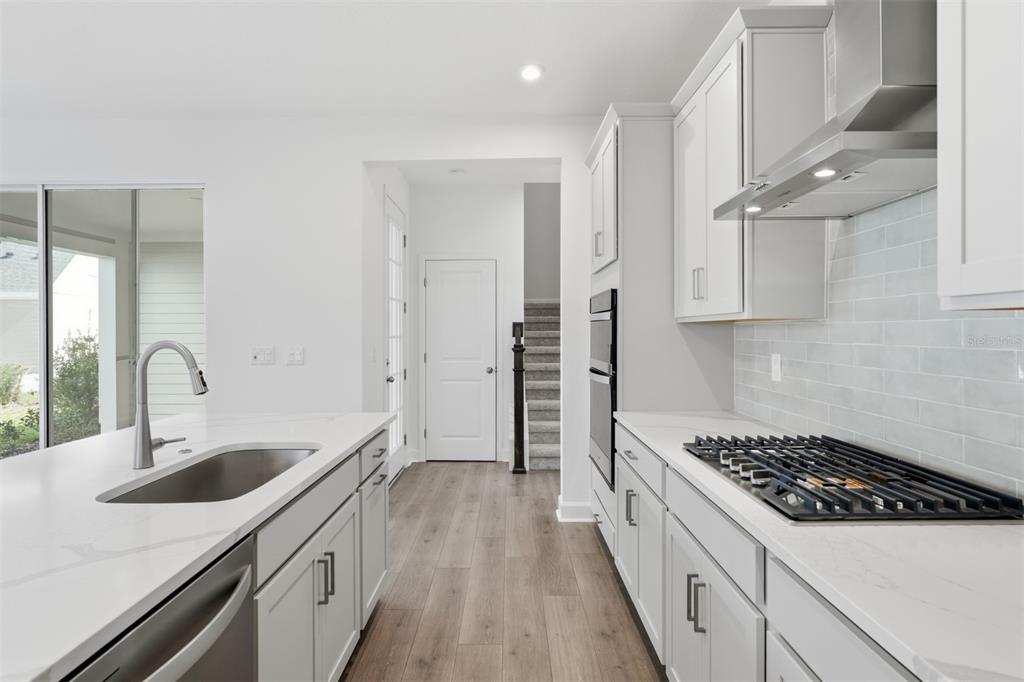 A modern kitchen features white cabinetry, a large island with a sink, and stainless appliances — 1931 SEAWALL WAY, CELEBRATION, FL