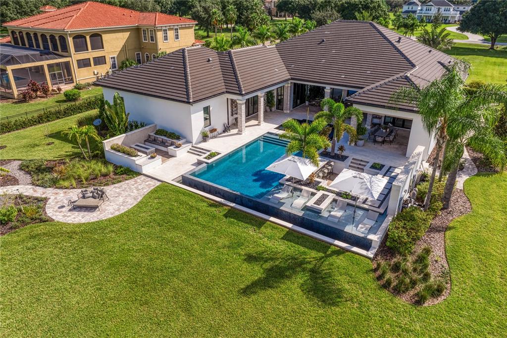 An aerial view of a house with a swimming pool, patio, and landscaped backyard — 10521 BROADLAND PASS, THONOTOSASSA, FL