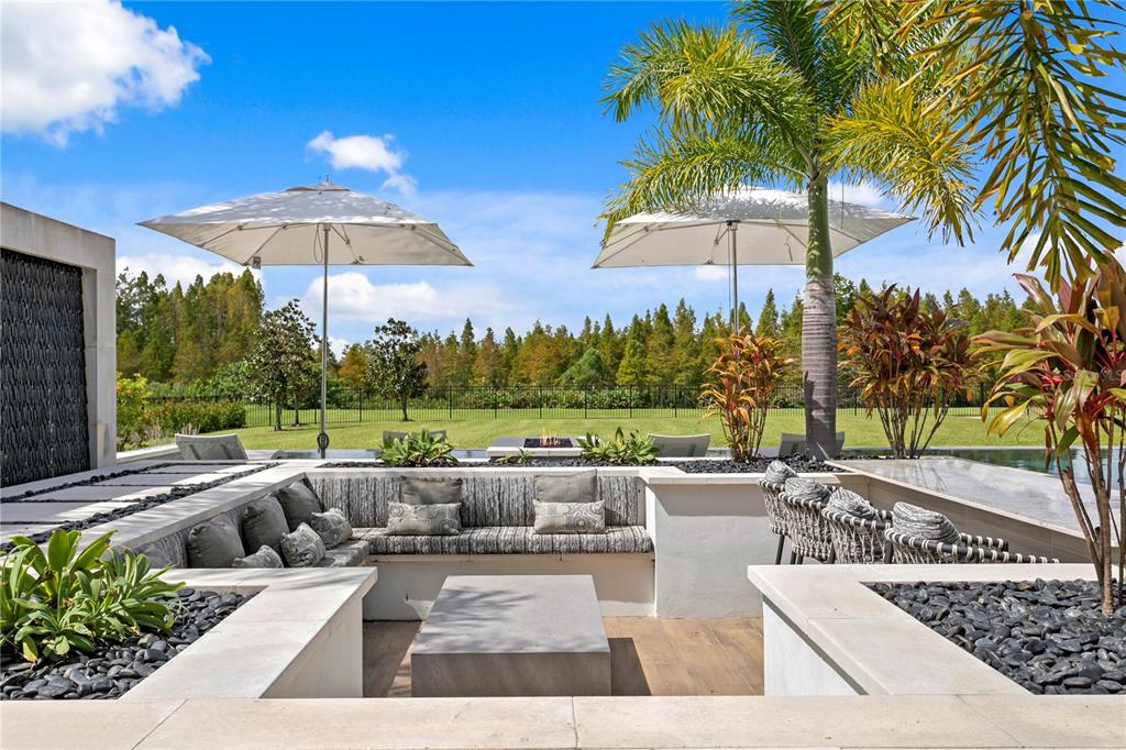A sunken outdoor seating area features a fire pit, built-in benches, and two patio umbrellas — 10521 BROADLAND PASS, THONOTOSASSA, FL