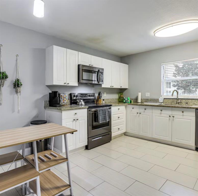 A kitchen features white cabinets, granite countertops, stainless steel appliances, and light-colored tile flooring — 2704 CLUB CORTILE CIRCLE, KISSIMMEE, FL