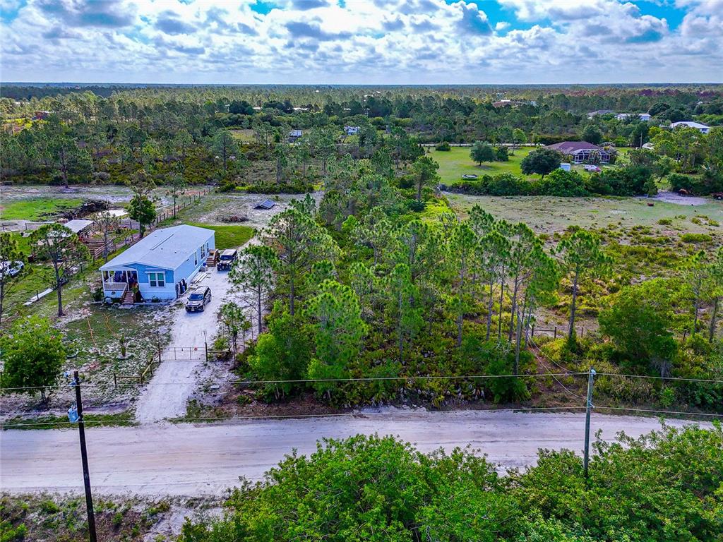 An aerial view shows a light blue manufactured home on a large, wooded rural lot — 8228 AUSTRIAN BOULEVARD, PUNTA GORDA, FL