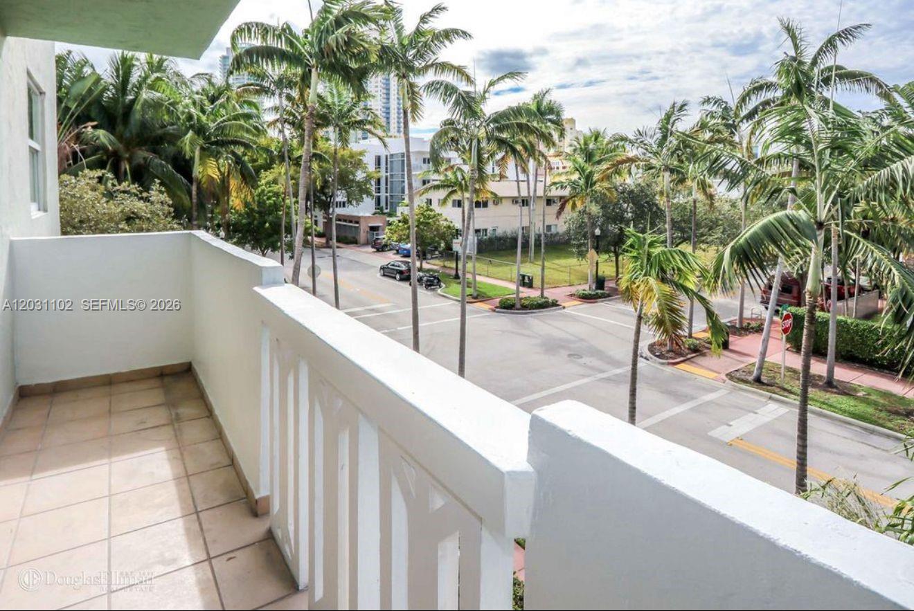 A balcony with tile flooring overlooks a street lined with palm trees and buildings — 301 Jefferson Ave # 3A, Miami Beach FL 33139, MIAMI BEACH, FL