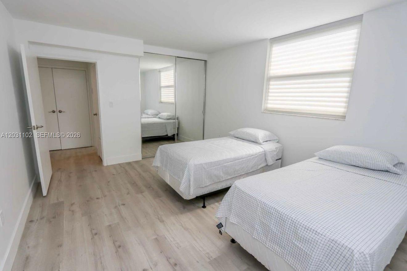 A bedroom features two twin beds, light wood-look flooring, and mirrored closet doors — 301 Jefferson Ave # 3A, Miami Beach FL 33139, MIAMI BEACH, FL
