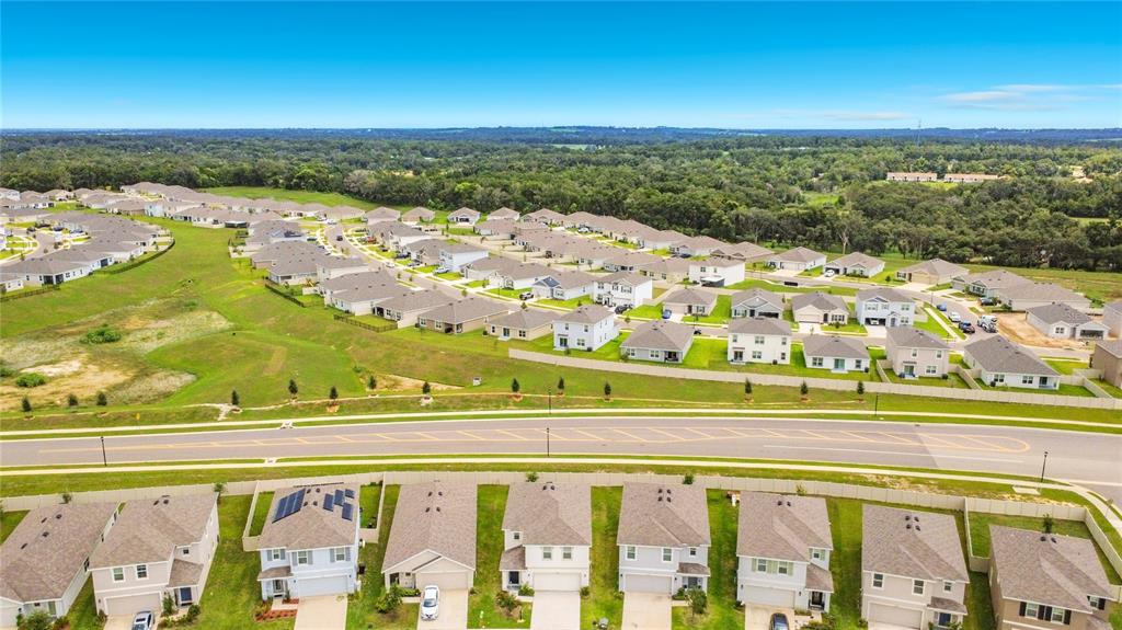 An aerial view shows a suburban neighborhood with rows of houses and a paved road — 35288 SPRUCE KNOB COURT, DADE CITY, FL