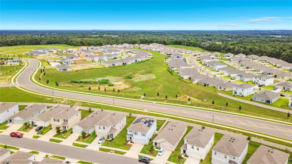 An aerial view shows a suburban neighborhood with numerous single-family homes and paved roads — 35288 SPRUCE KNOB COURT, DADE CITY, FL