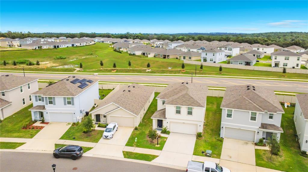 An aerial view shows several suburban houses with driveways and lawns near a paved road — 35288 SPRUCE KNOB COURT, DADE CITY, FL
