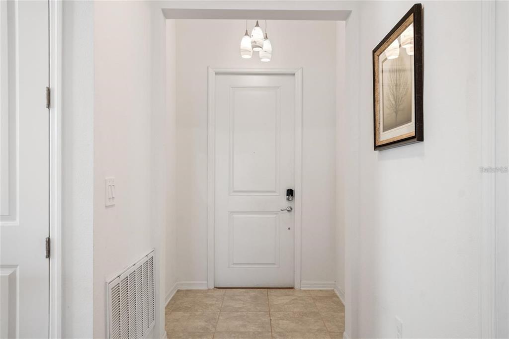 A white front door with a digital lock sits at the end of a tiled entryway — 1172 TYLER LOOP, WINTER HAVEN, FL