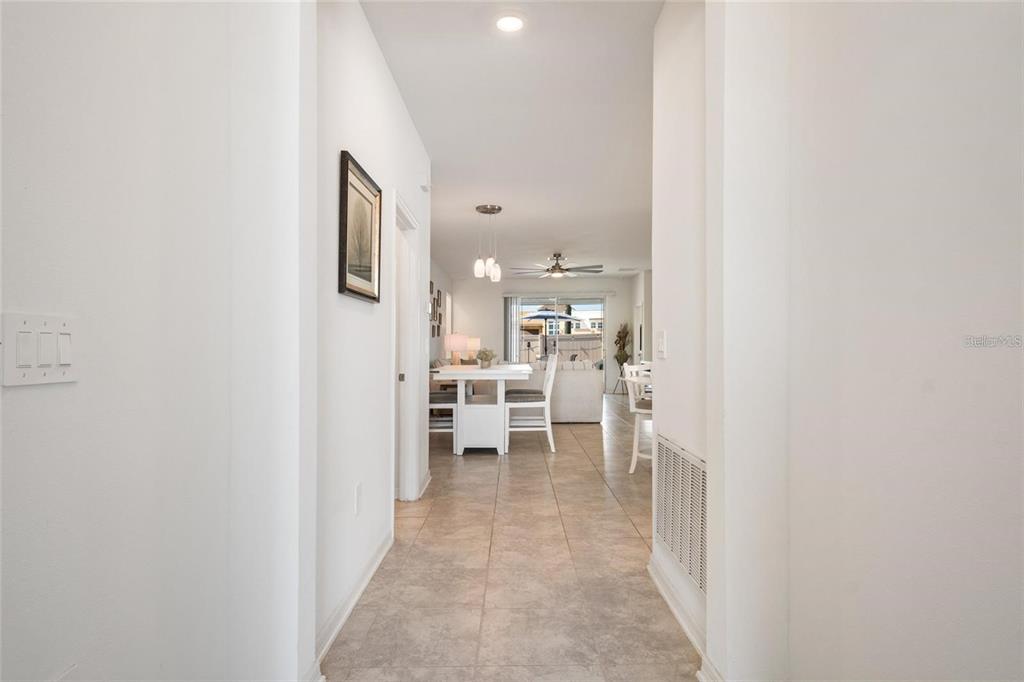 A hallway with tile flooring leads to a dining area and living space beyond — 1172 TYLER LOOP, WINTER HAVEN, FL