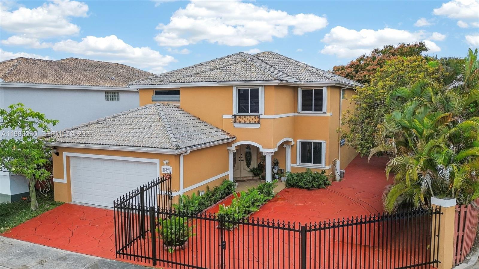 A two-story orange house features a tiled roof, a garage, and a red paved driveway — 15672 SW 91st Ln, Miami FL 33196, MIAMI, FL