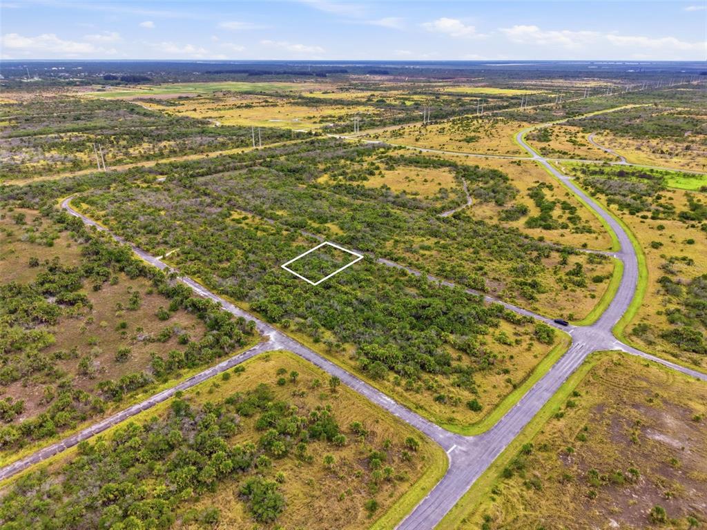 An aerial view shows a vacant, brush-covered lot outlined in white within a rural subdivision — 1553 ALCOVA STREET SW, PALM BAY, FL