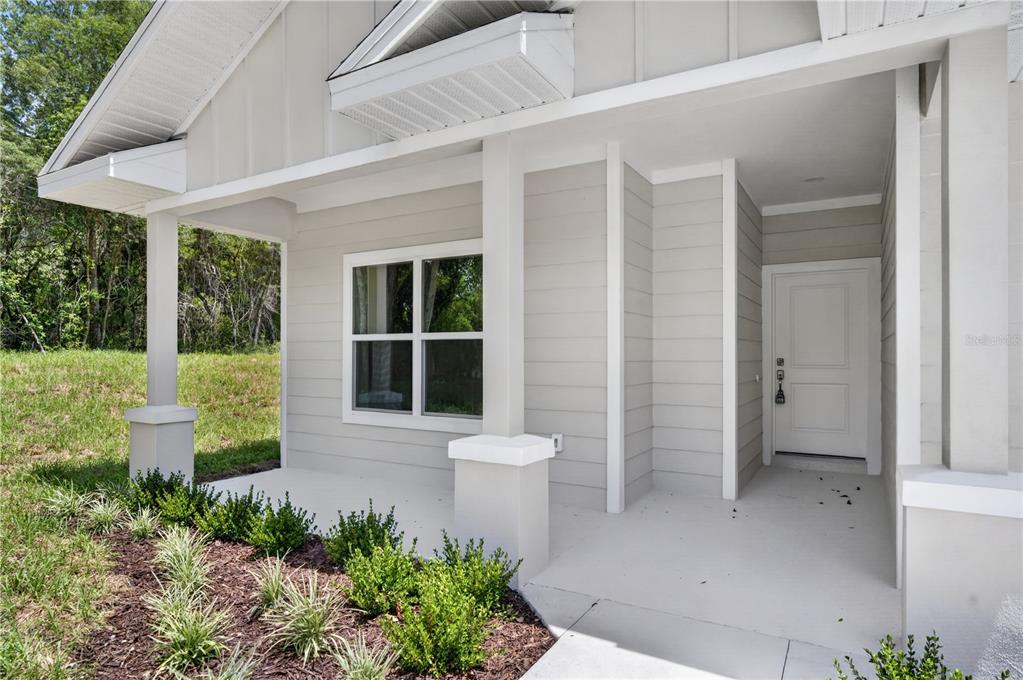A covered front porch with light gray siding, a white door, and a single window — 631 S ANCHOR DRIVE, DELTONA, FL