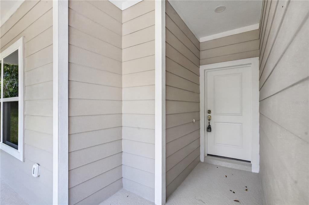 A beige-sided house exterior features a white front door under a covered entryway — 631 S ANCHOR DRIVE, DELTONA, FL