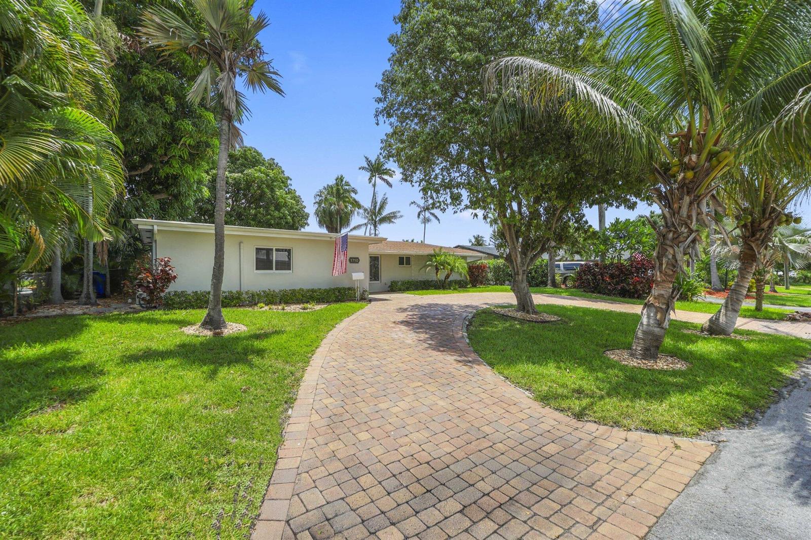 A single-story house with a paved driveway and palm trees under a clear blue sky — 1710 SW 4th Avenue, Pompano Beach FL 33060, POMPANO BEACH, FL