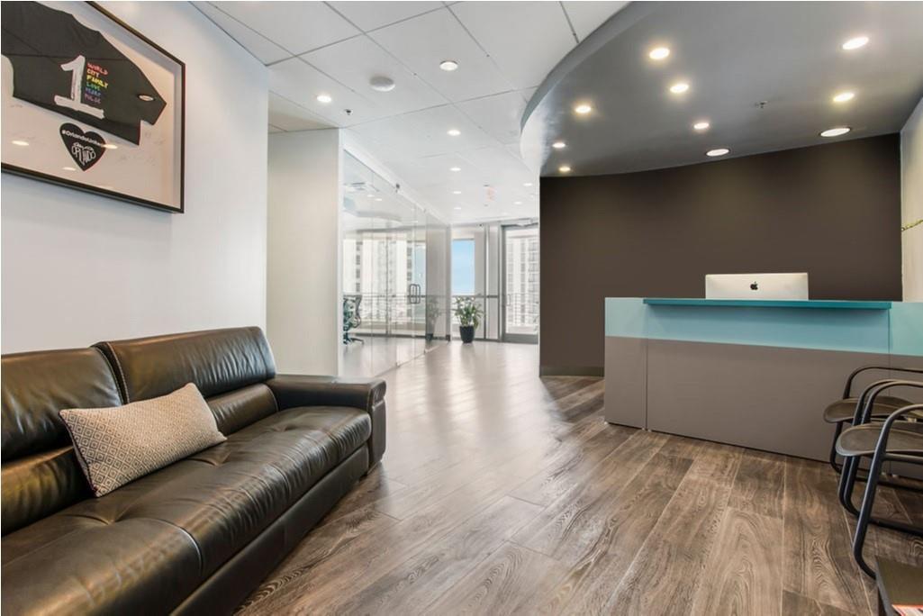 A modern office reception area features a black leather sofa, wood-look flooring, and a curved desk — 121 S Orange Avenue # 1470N, FL 32801, FL