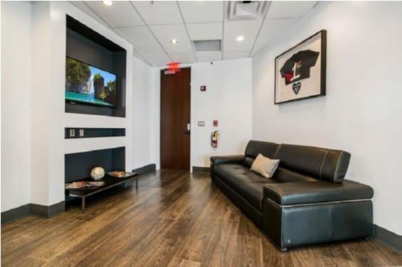 A waiting area features a black leather sofa, a wall-mounted television, and wood-look flooring — 121 S Orange Avenue # 1470N, FL 32801, FL