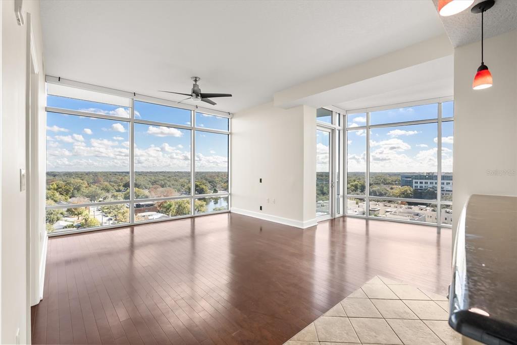 An empty living room with hardwood floors, floor-to-ceiling windows, and a ceiling fan — 101 S EOLA DRIVE UNIT 1010, ORLANDO, FL