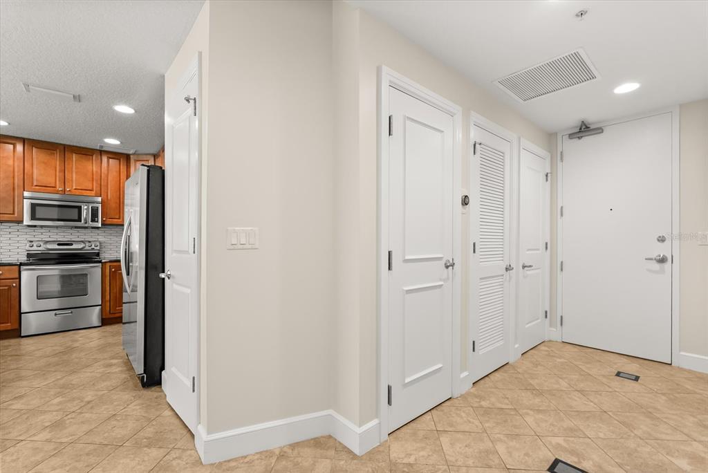 A tiled entryway features three white doors, a light-colored wall, and a view into a kitchen — 101 S EOLA DRIVE UNIT 1010, ORLANDO, FL