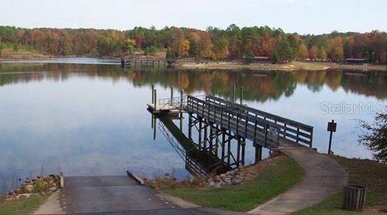 A wooden boat dock extends into a calm lake surrounded by trees with autumn foliage — 3065 W MARIE DRIVE, CITRUS SPRINGS, FL