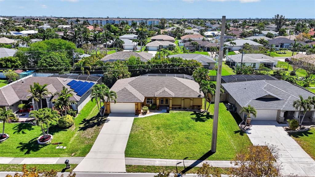 An aerial view shows a suburban house with a tan exterior and a large lawn — 3809 AGUALINDA BOULEVARD, CAPE CORAL, FL