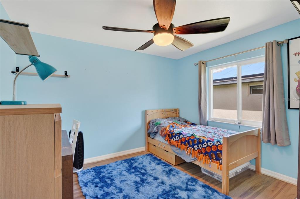 A bedroom with light blue walls, a wooden bed frame, and a blue shag rug — 3809 AGUALINDA BOULEVARD, CAPE CORAL, FL